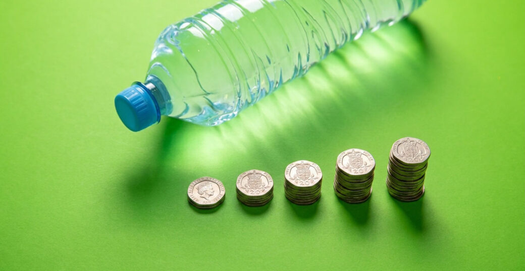 Plastic bottle with stacks of 20p coins, illustrating the 20p deposit on DRS.